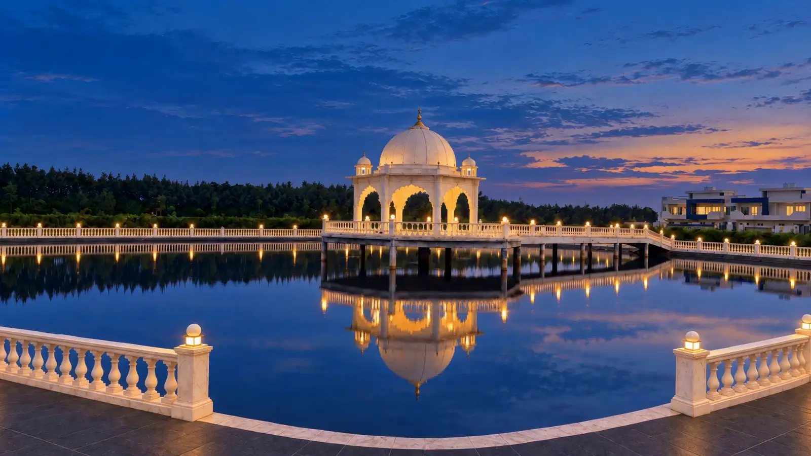 The pond at blue hour, the white marble mandap lit on its stage and doubled in the water