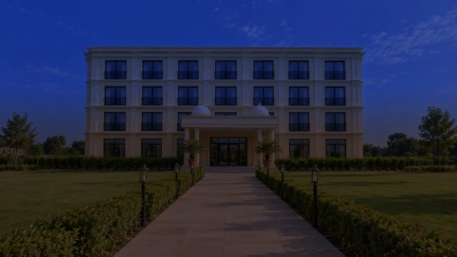 The hotel at blue hour, a path across the lawn to its lit porch