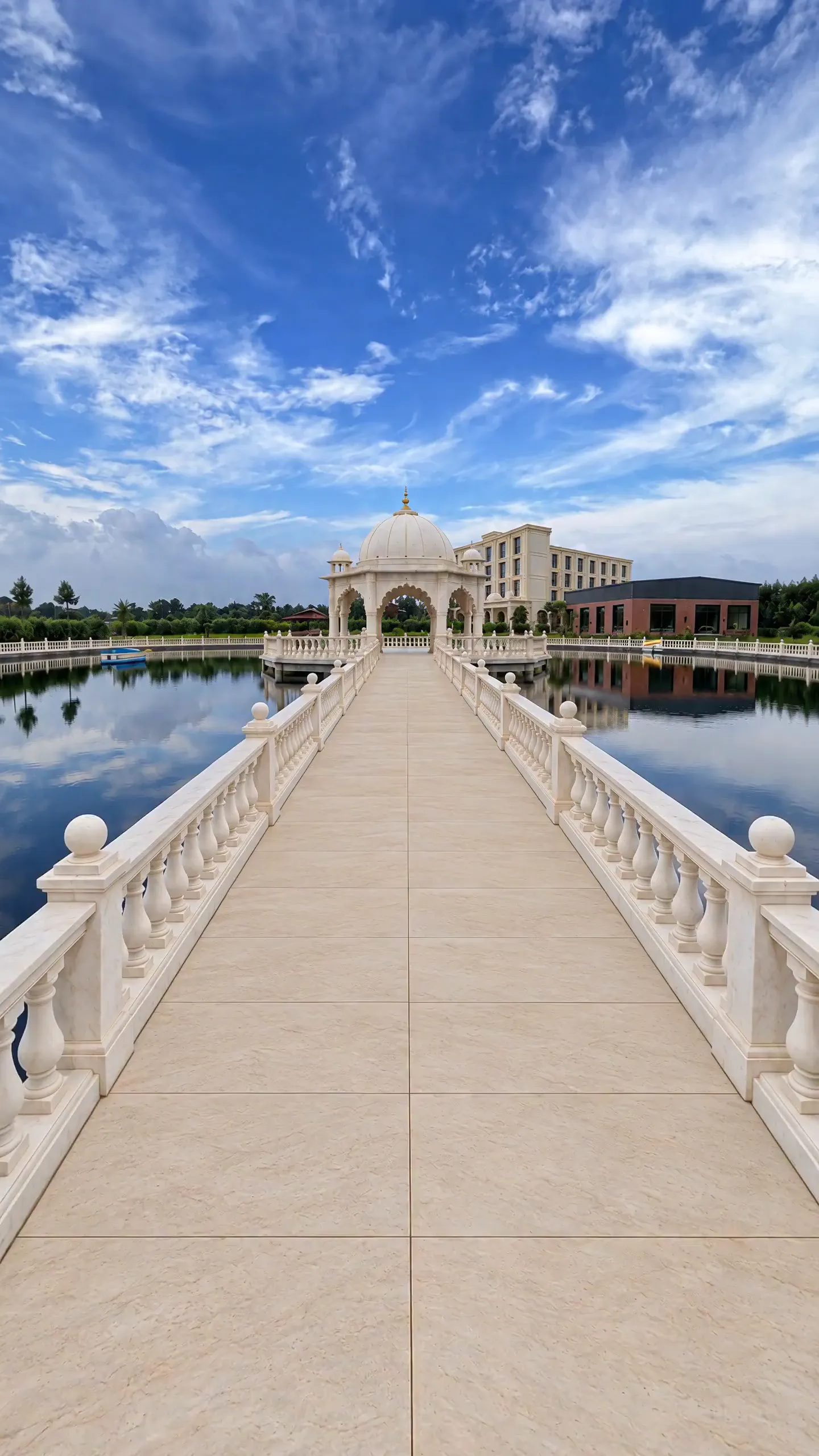 Looking along the railed white causeway across the pond to the domed marble mandap