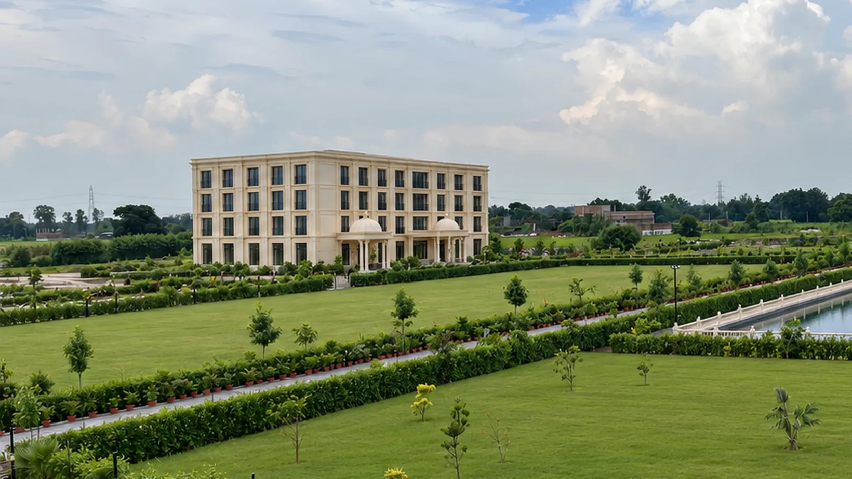 The lawn in front of the hotel by day: clipped hedges, young trees and a path to the covered porch