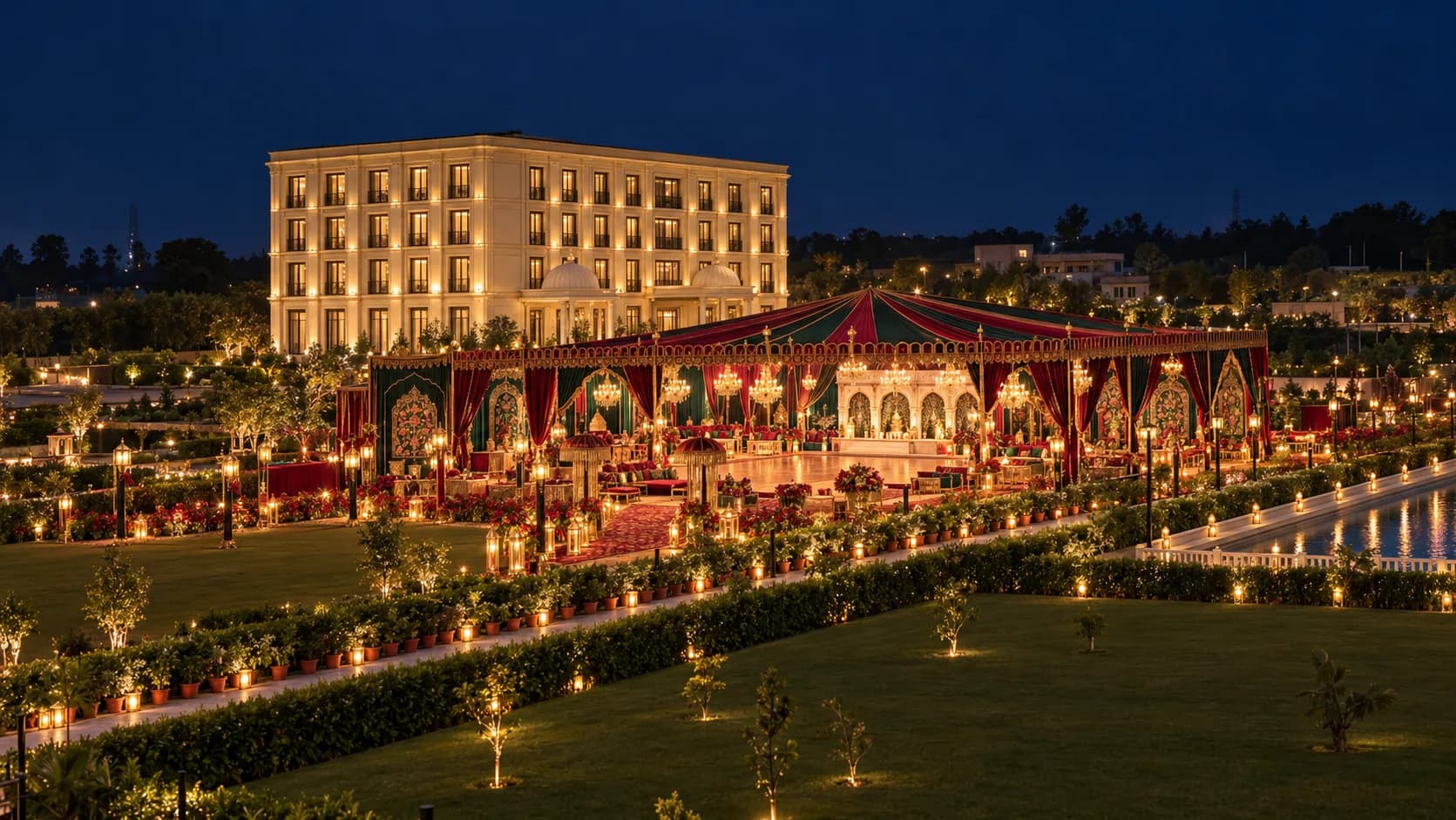 The same lawn at night, dressed for a sangeet under a red and green canopy, lamps along every hedge
