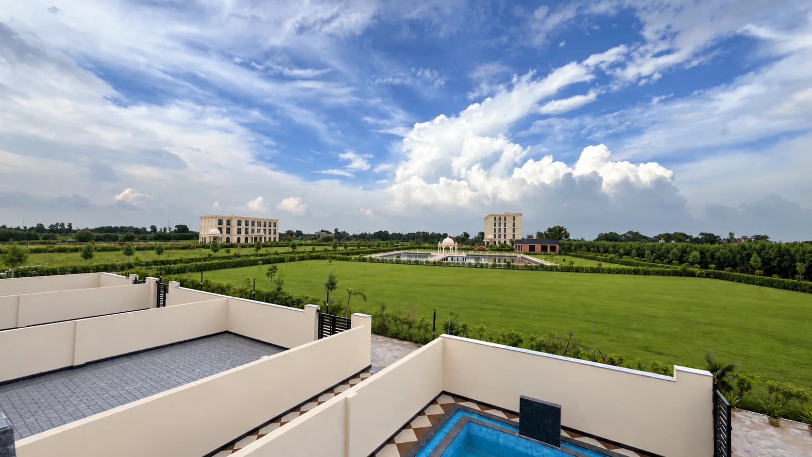 From a villa roof across the courtyards to the open lawn, with the hotel and the pond far off under a big sky