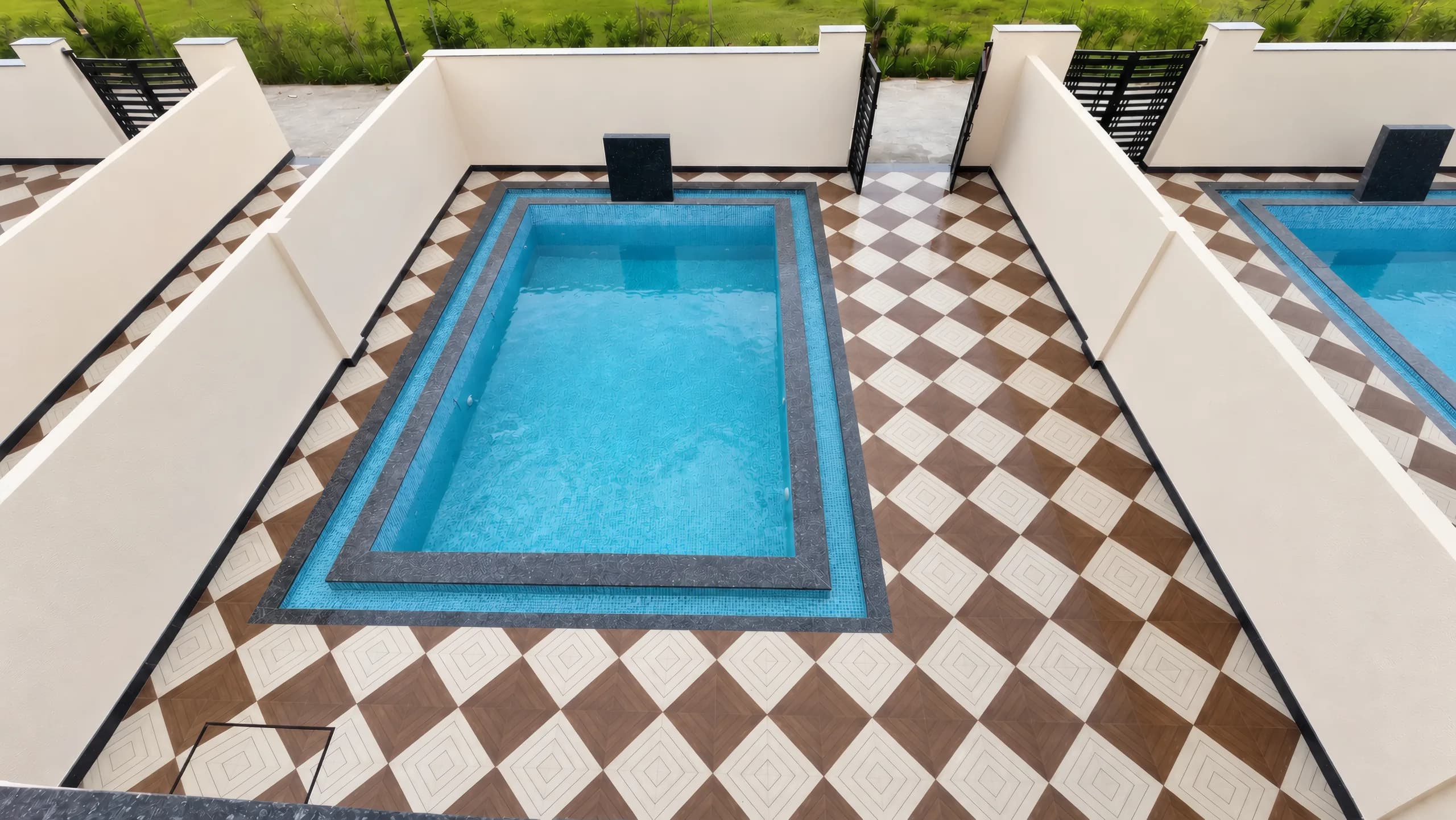 Looking down from a villa roof at a courtyard's plunge pool and its brown and cream checkerboard tiles