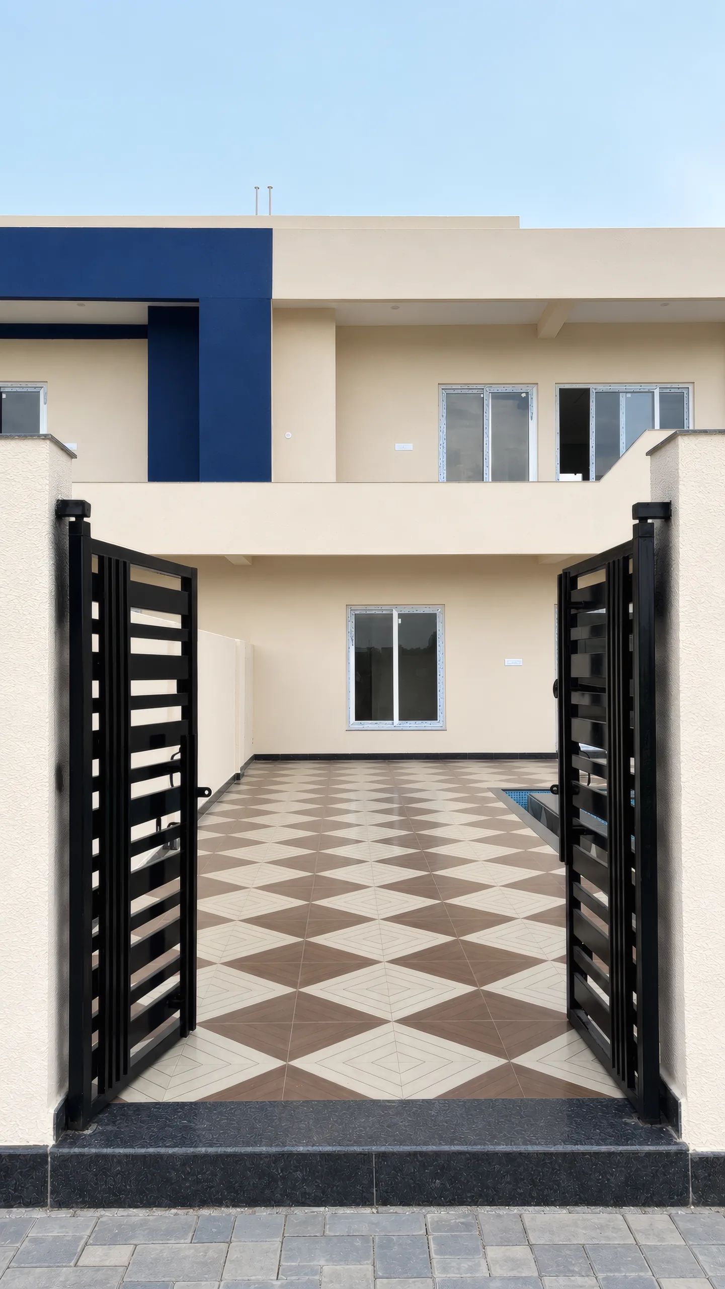 A villa's black slatted gate standing open onto its checkerboard courtyard