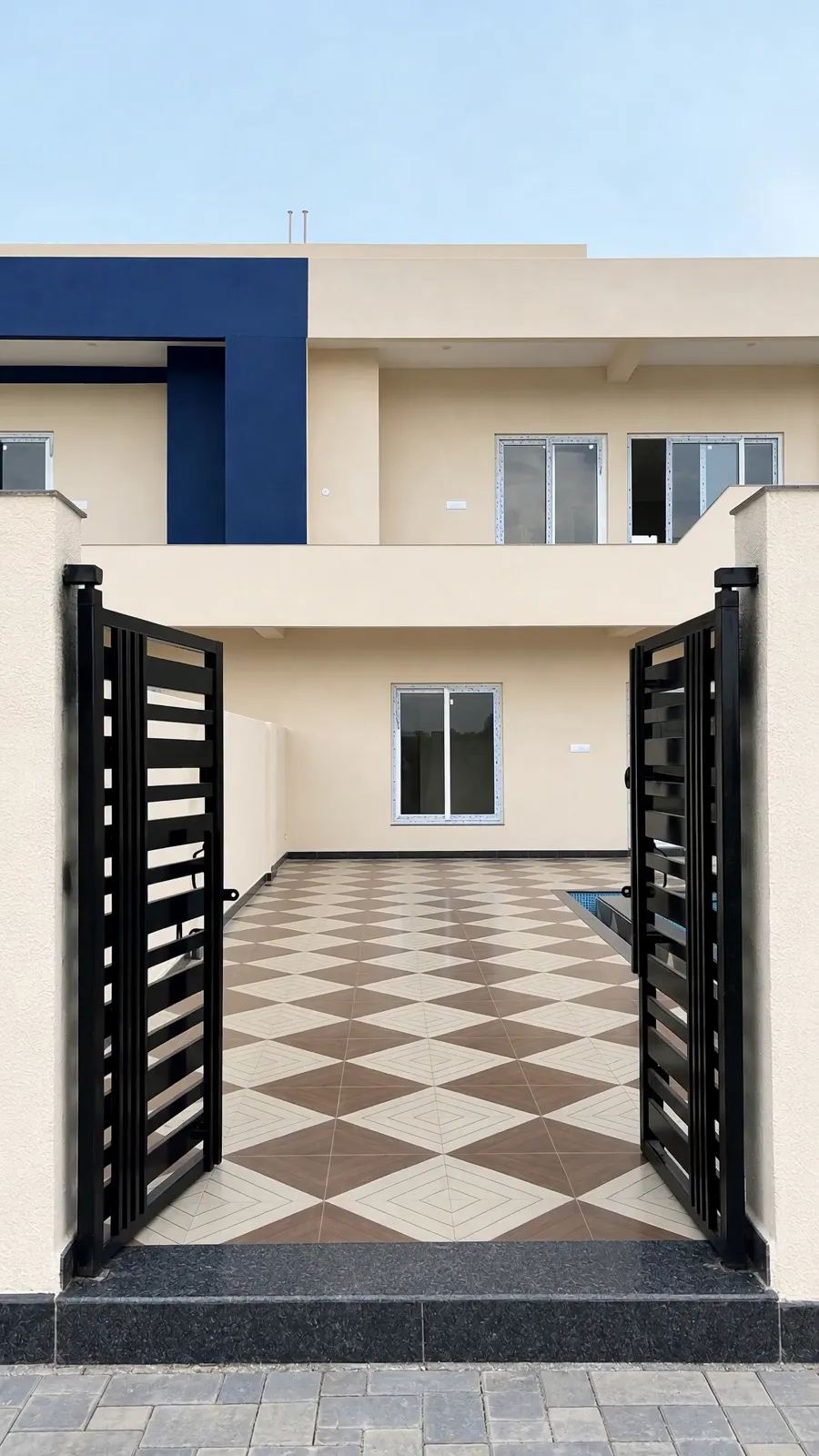 A villa's black slatted gate standing open onto its checkerboard courtyard, the two-storey house beyond